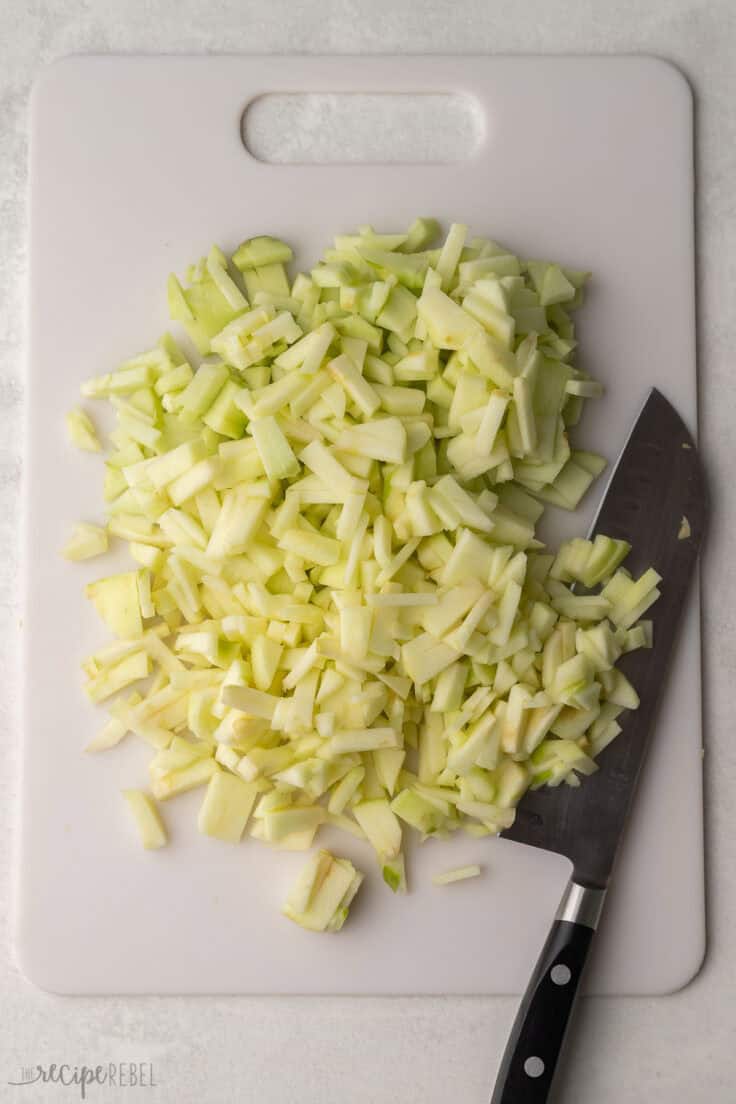 chopped apple on a white cutting board with knife beside.