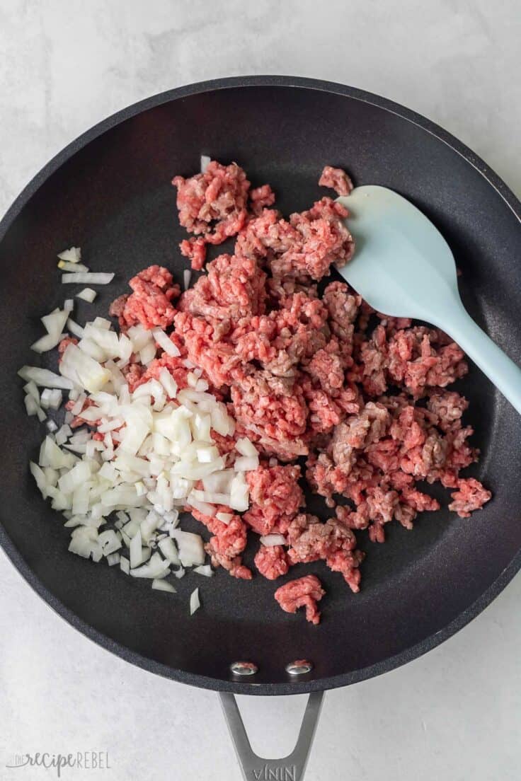 ground beef and onions in black frying pan.