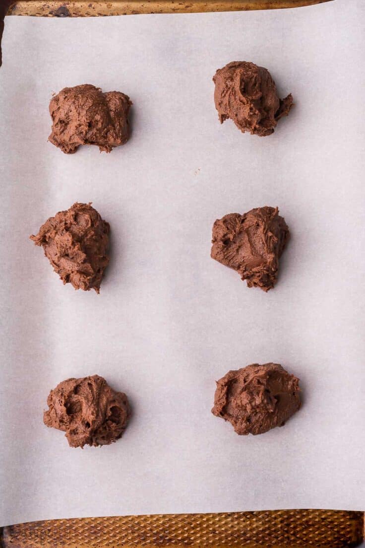 six balls of cookie dough on a parchment lined pan.