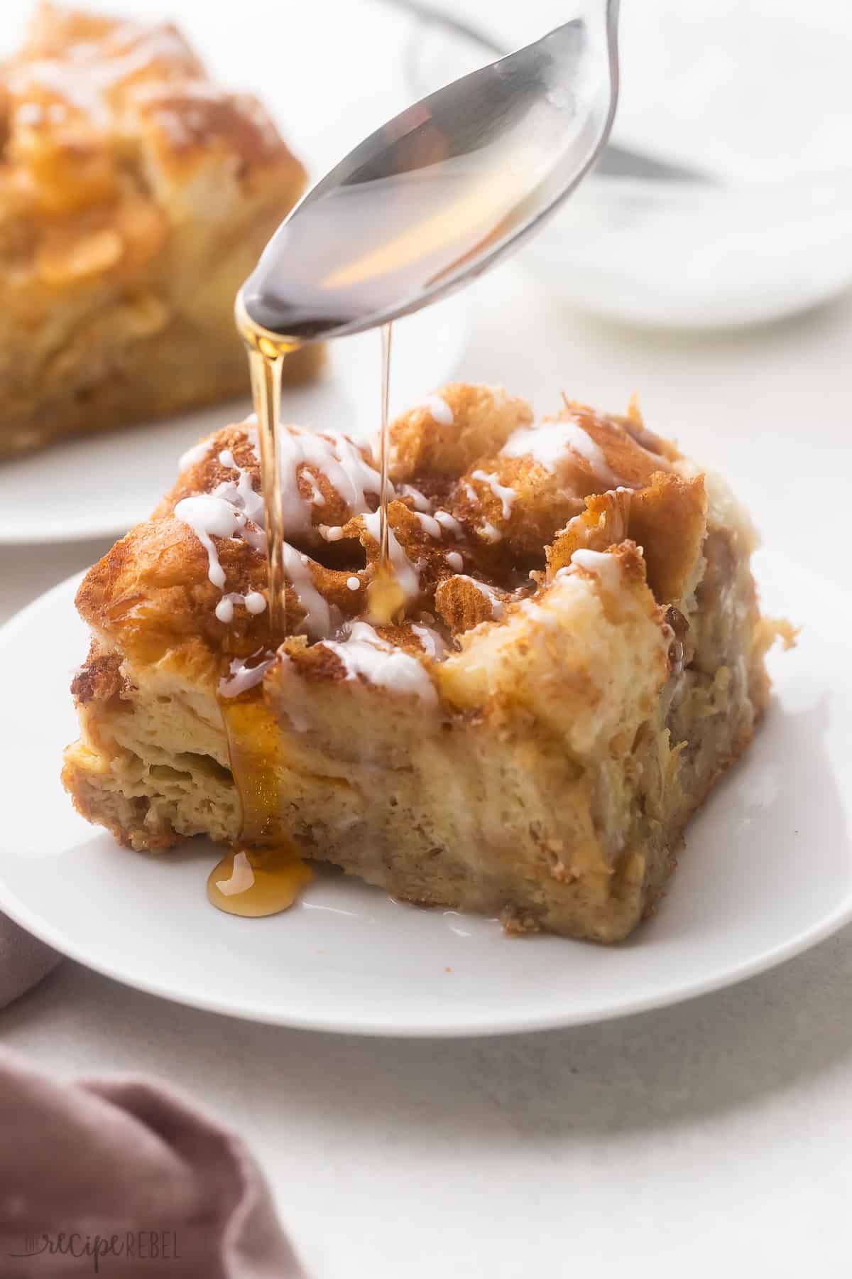 a spoon pouring syrup over a piece of french toast casserole.