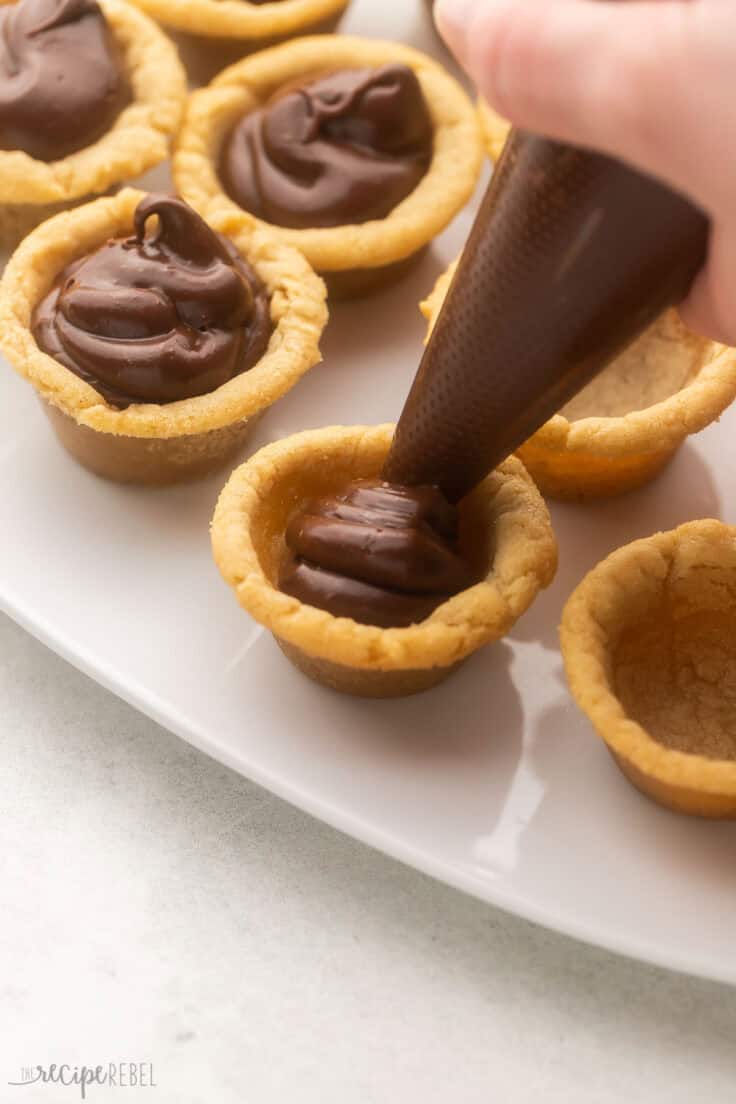 a frosting bag filling fudge into the crusts.