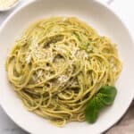 overhead square image of pesto pasta in a shallow white bowl.