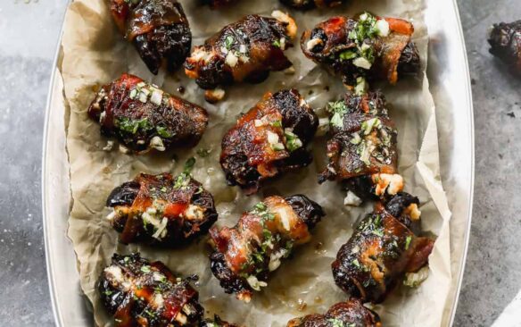 dates with bacon wrapped around them sprinkled with a green garnish