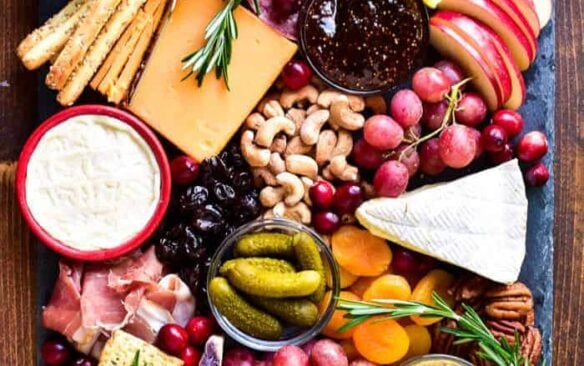 picture of cheese, meat, fruit, nuts, pickles, and olives on a tray