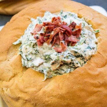 piece of bread with hole cut in the middle and filled with bacon spinach dip