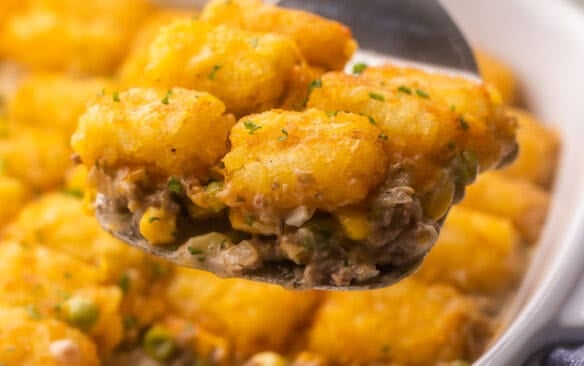 square image of tater tot casserole being lifted out of pan.