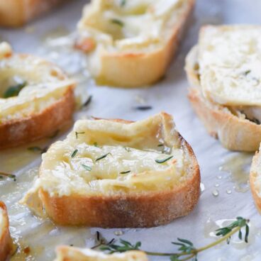 toasted baguette slices topped with melted brie cheese, honey, and herbs