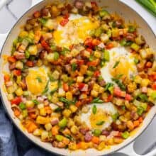 breakfast skillet in large white pan with eggs beside in bowl.