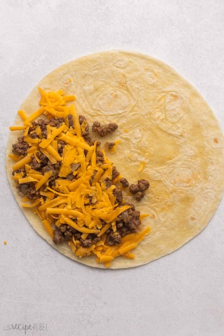 a flat tortilla with taco meat and shredded cheese.