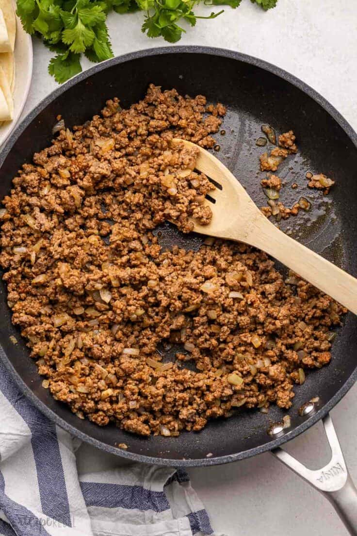 cooked taco meat in pan with wooden ladle.