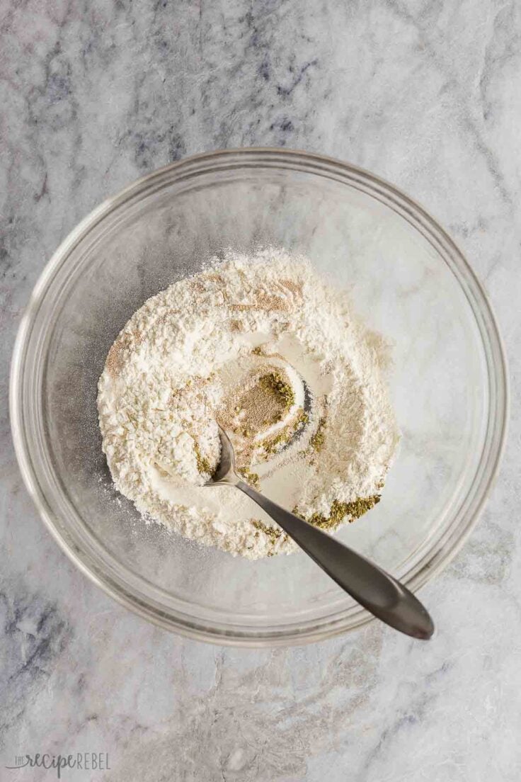 dry ingredients in glass mixing bowl with spoon.