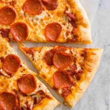 pepperoni pizza with a slice cut out on marble surface.