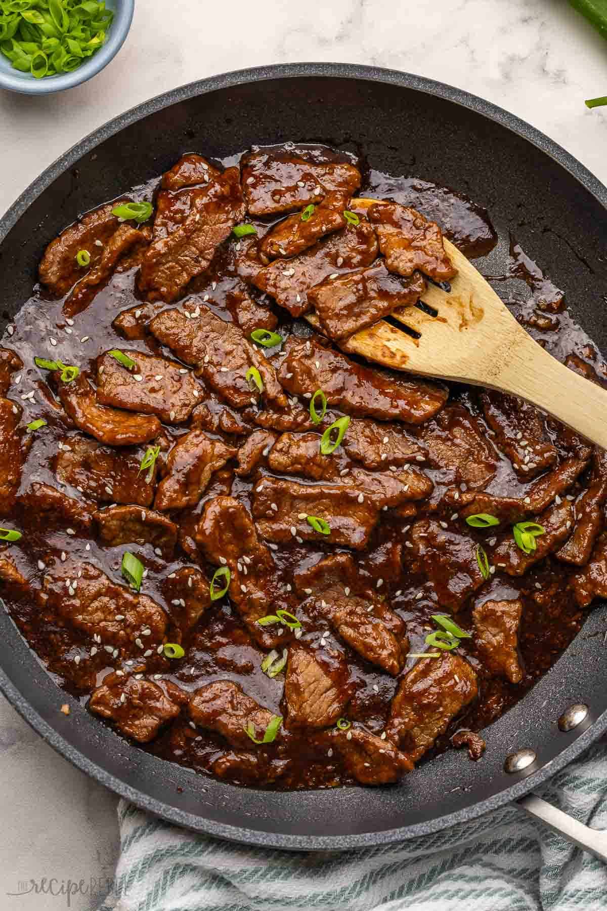 black pan of maple ginger beef with wooden ladle beside.