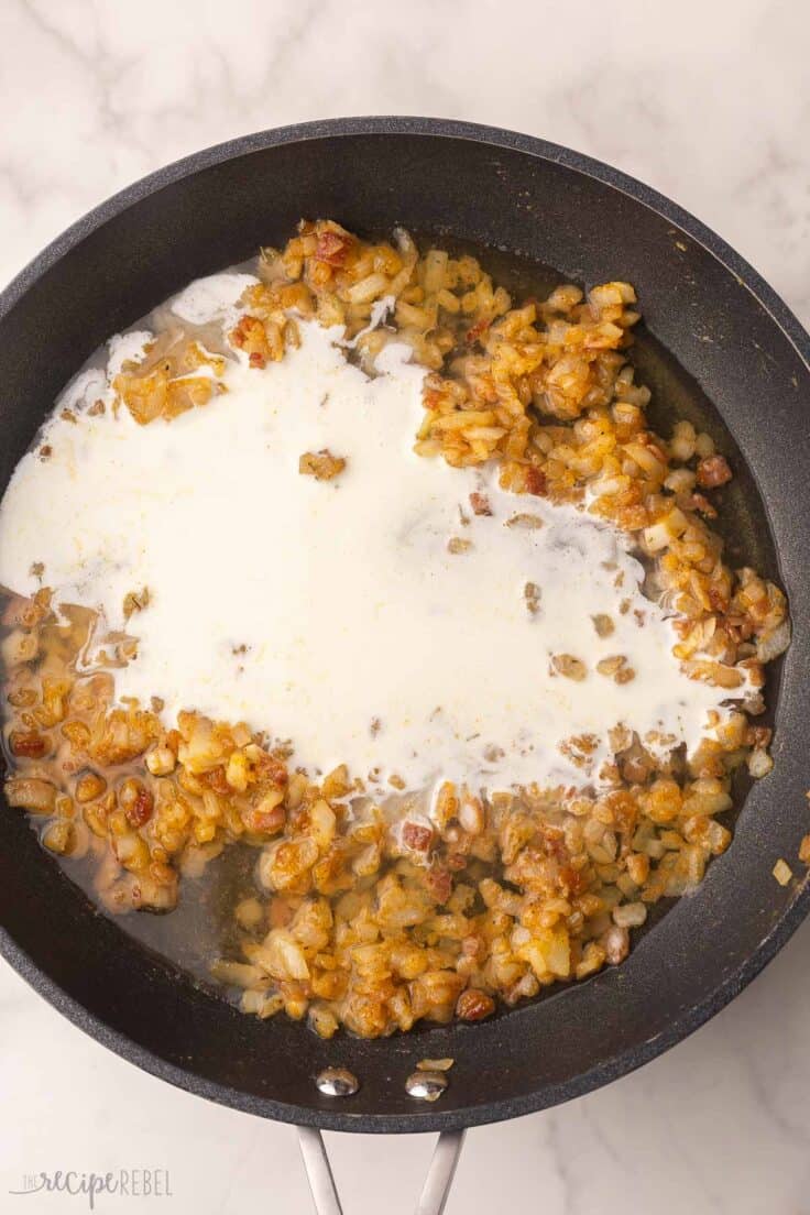 cream added to other ingredients in black pan.