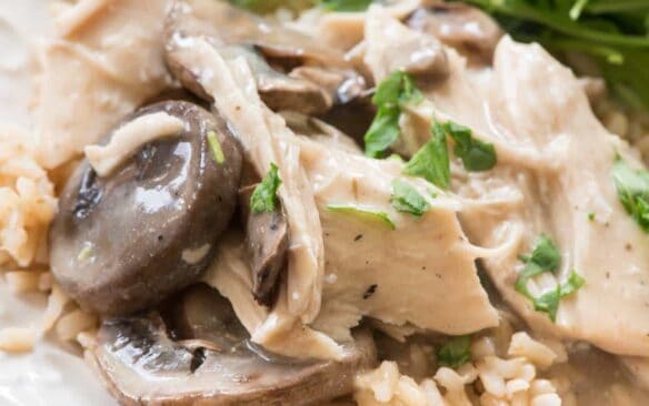 close up of creamy mushroom chicken with a side salad on a white plate