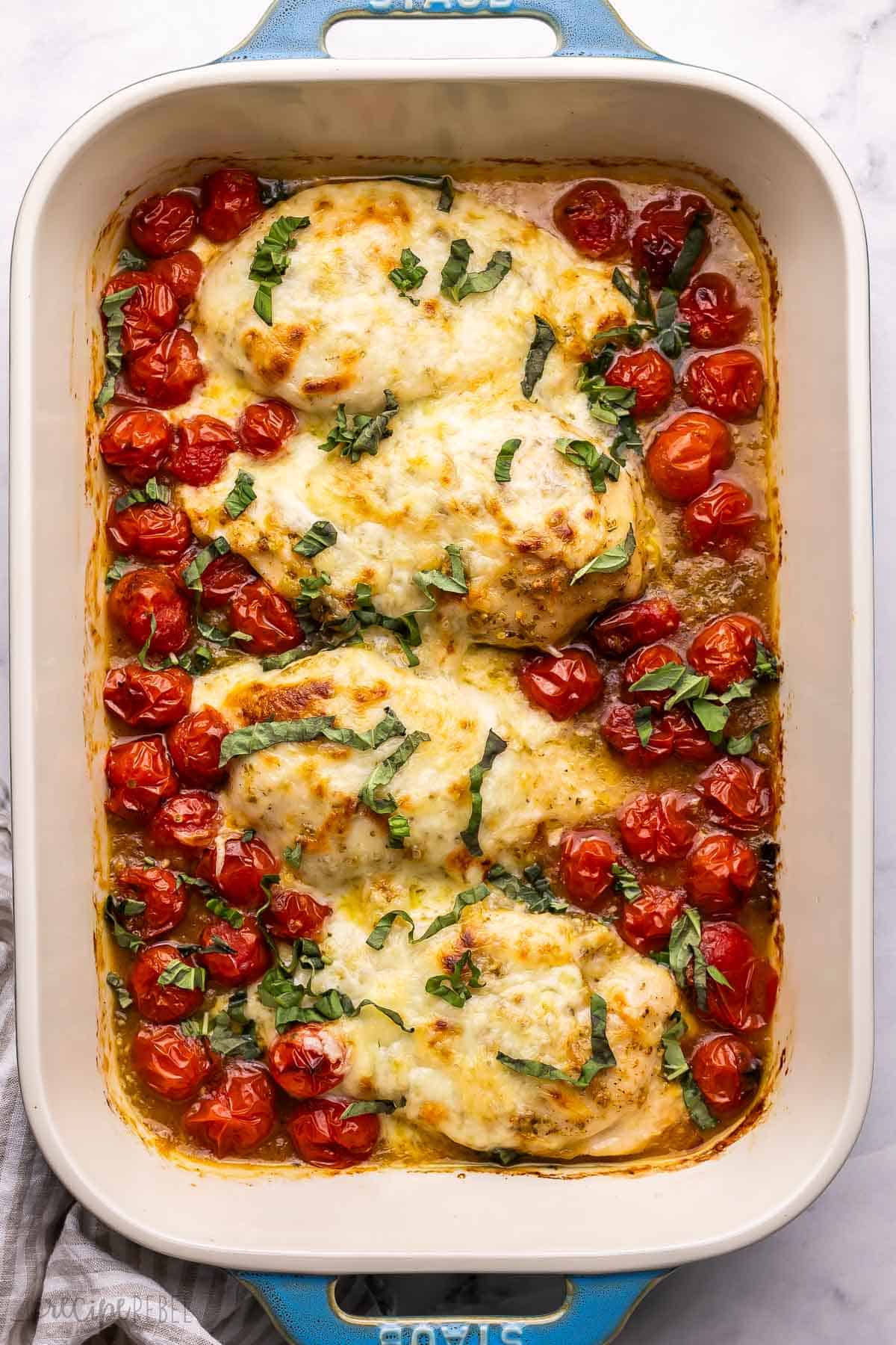 baked caprese chicken in blue and white baking dish.