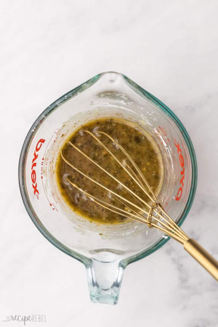 glass measuring cup with sauce ingredients and a golden whisk.