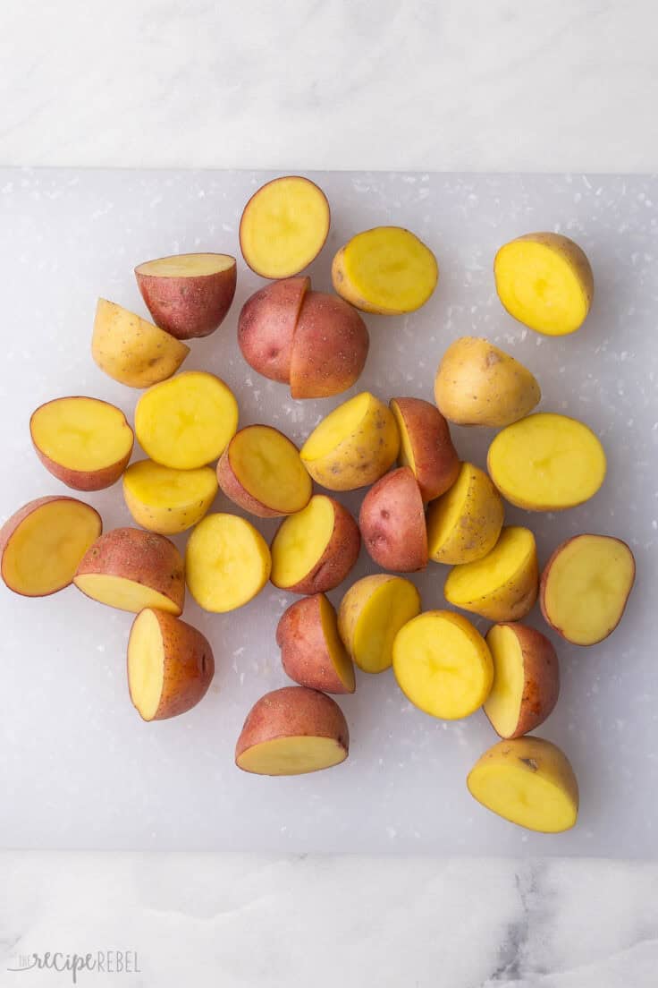 small potatoes lying on a white cutting board halved.