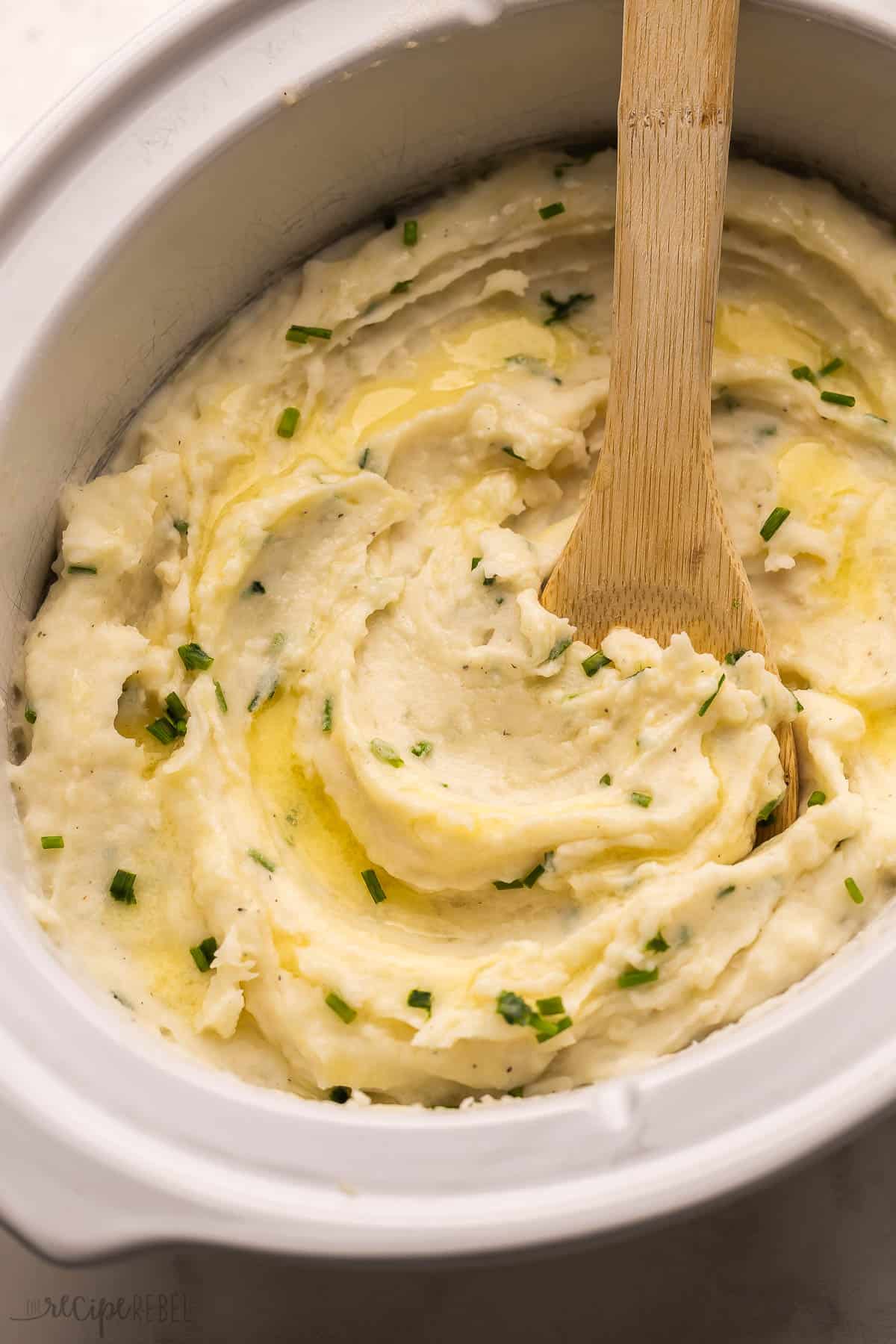 These Slow Cooker Mashed Potatoes are just as rich and creamy as stove top mashed potatoes with less of the work! The perfect hands-off side dish for any holiday dinner! #slowcooker #crockpot #mashedpotatoes #recipe slow cooker mashed potatoes topped with chopped green onions.