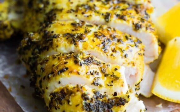 baked lemon pepper chicken breast sliced on cutting board.