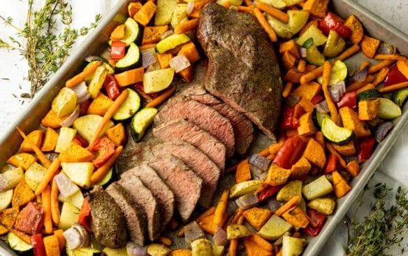 London Broil surrounded by vegetables on a sheet pan