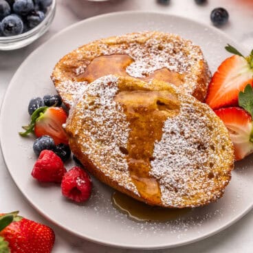 a plate of air fryer french toast topped with powdered sugar and syrup.