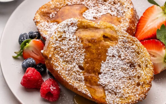 a plate of air fryer french toast topped with powdered sugar and syrup.