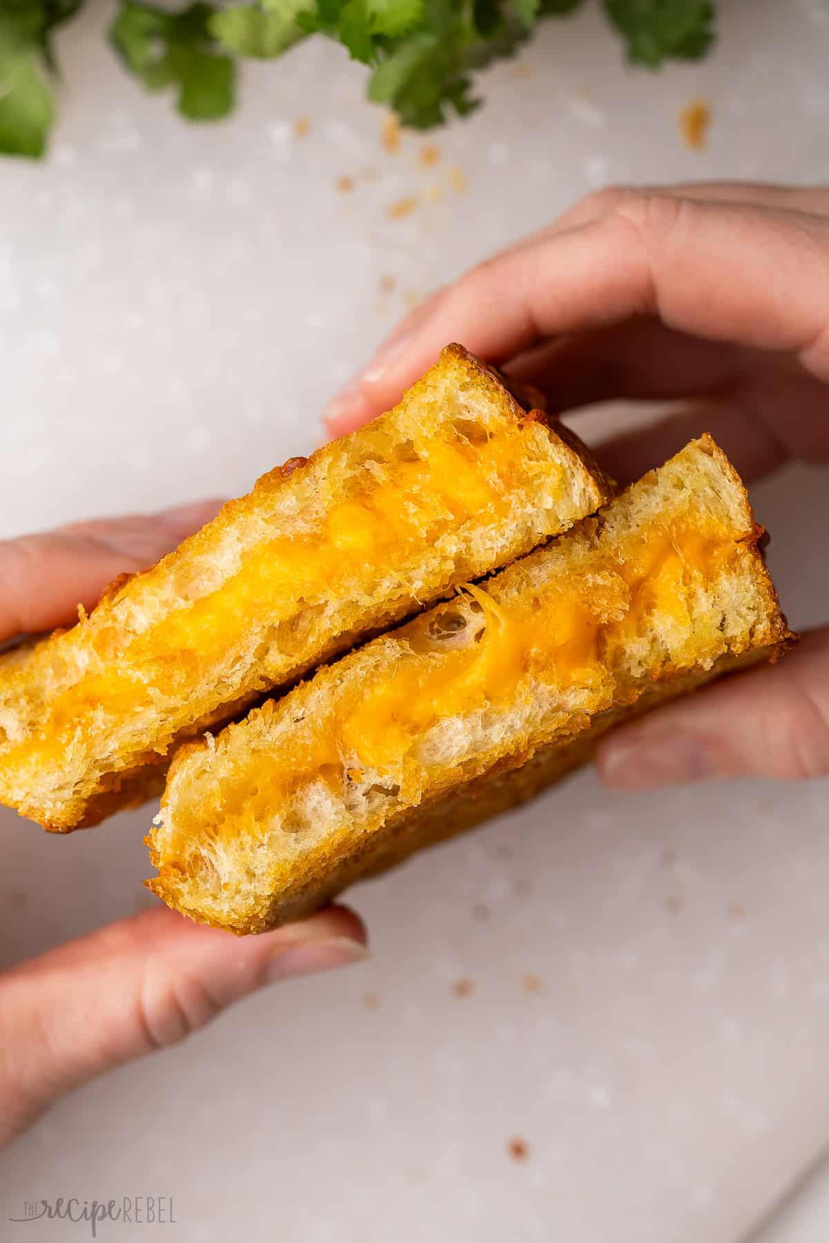 hands holding two air fryer grilled cheese sandwiches.