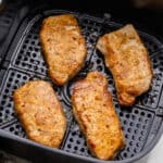 four air fryer pork chops in black air dryer basket.
