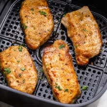 air fryer basket with four cooked pork chops in it.