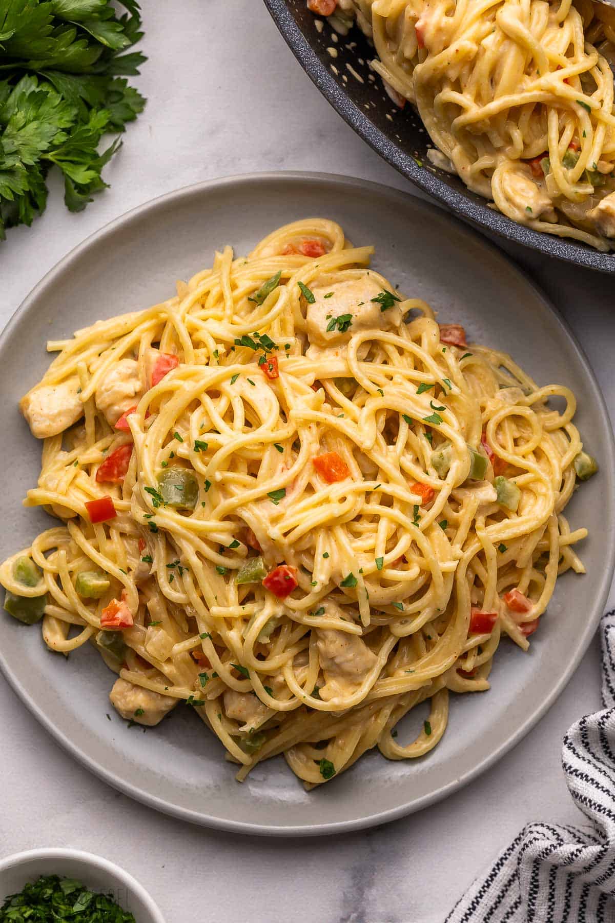 large plate filled with chicken spaghetti with parsley beside.