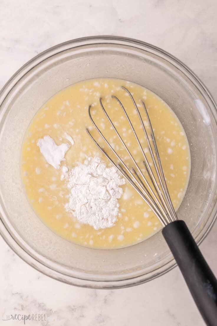 glass mixing bowl with wet ingredients and whisk.