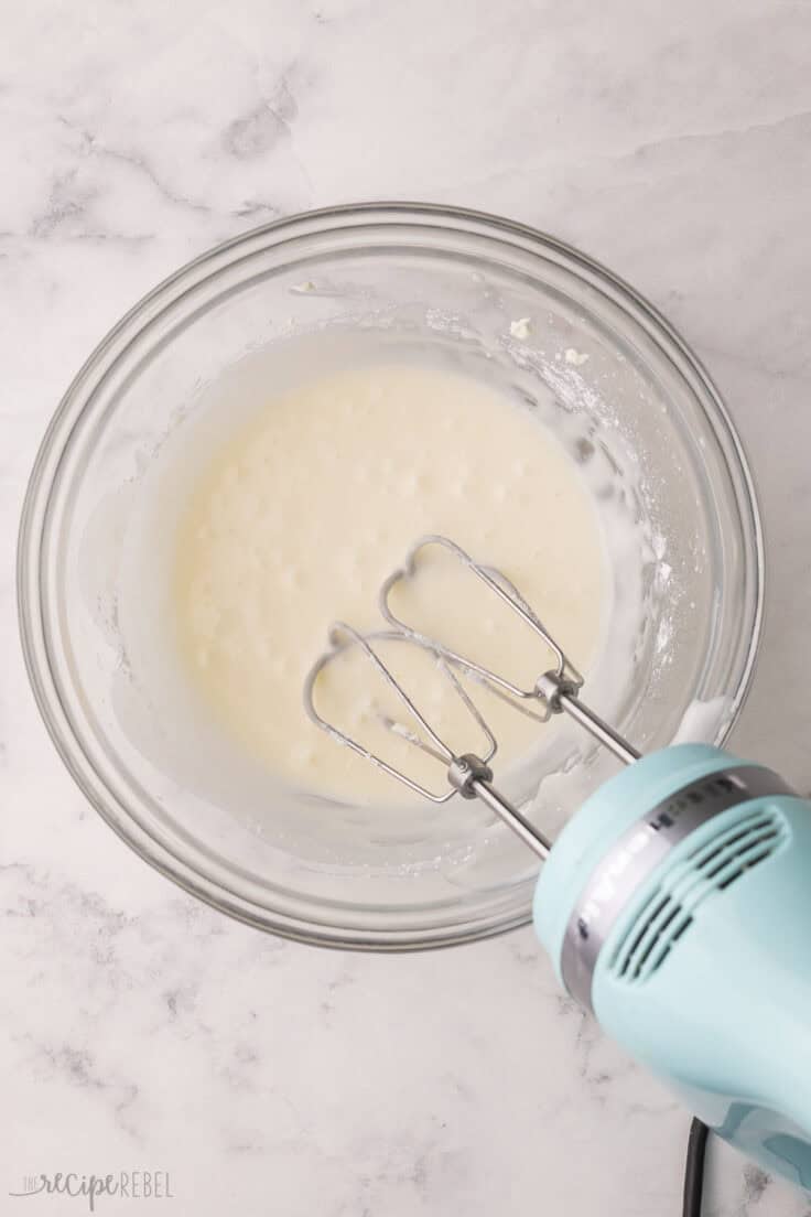 glass mixing bowl with electric mixer and coconut bread glaze.