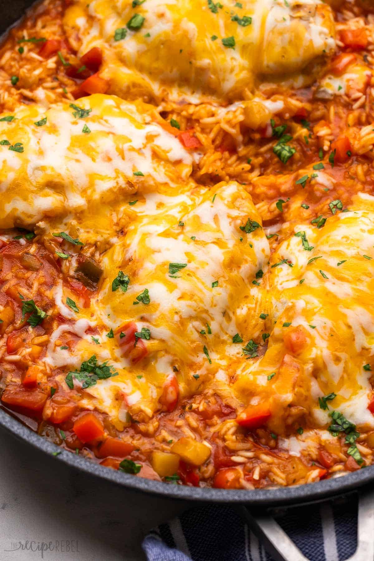 mango salsa chicken and rice in pan covered in melted cheese and chopped parsley.
