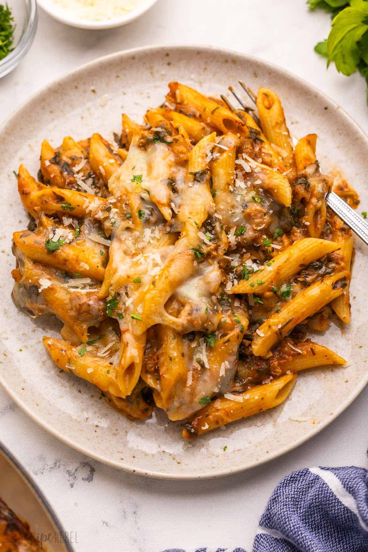 speckled plate full of baked ziti and a fork.