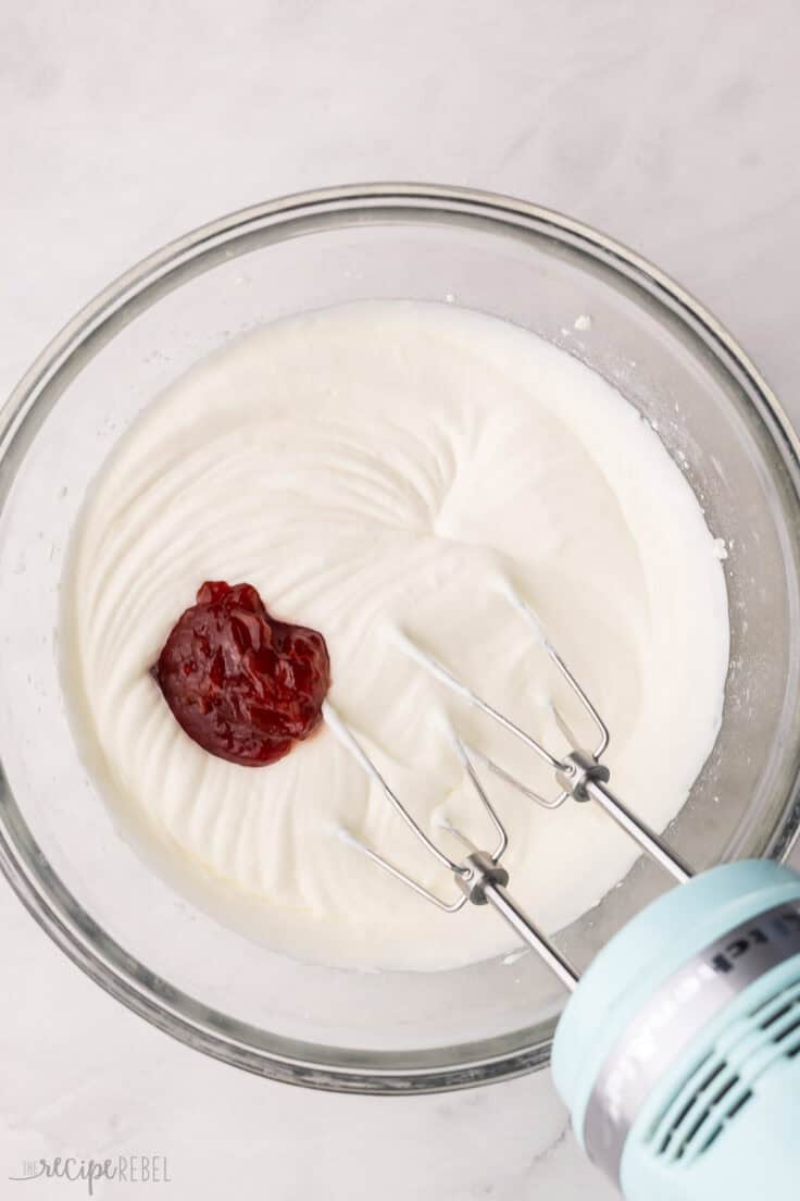 large bowl of whipped cream with strawberry jam added.