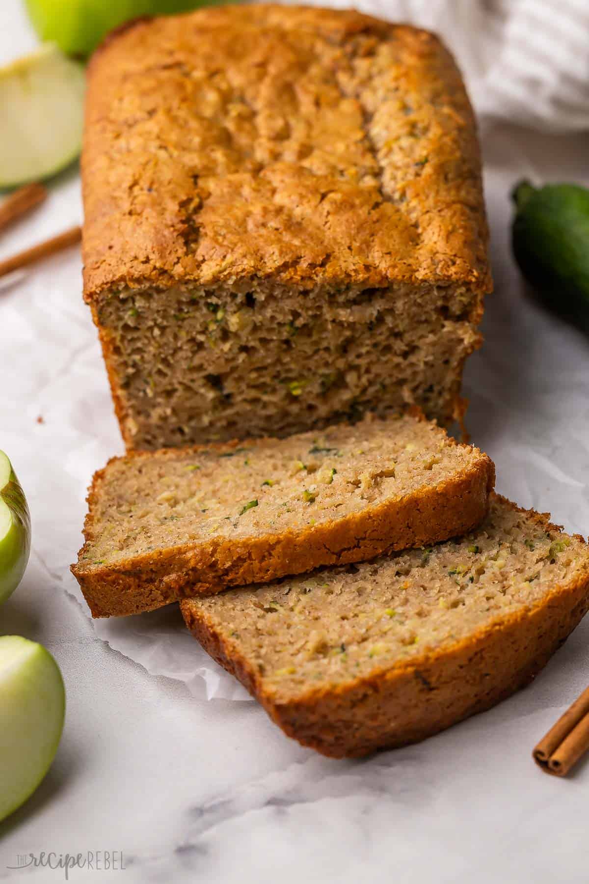 slices of zucchini apple bread with cinnamon sticks and apple slices beside.