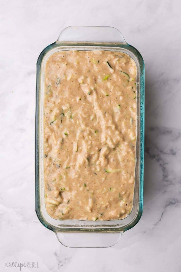 a glass loaf pan filled with zucchini apple bread batter.