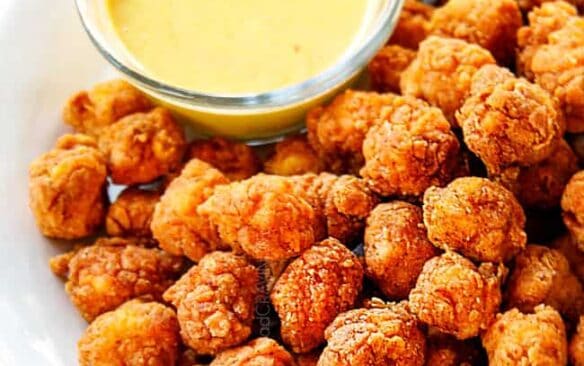 popcorn chicken on a white plate with a side of honey mustard