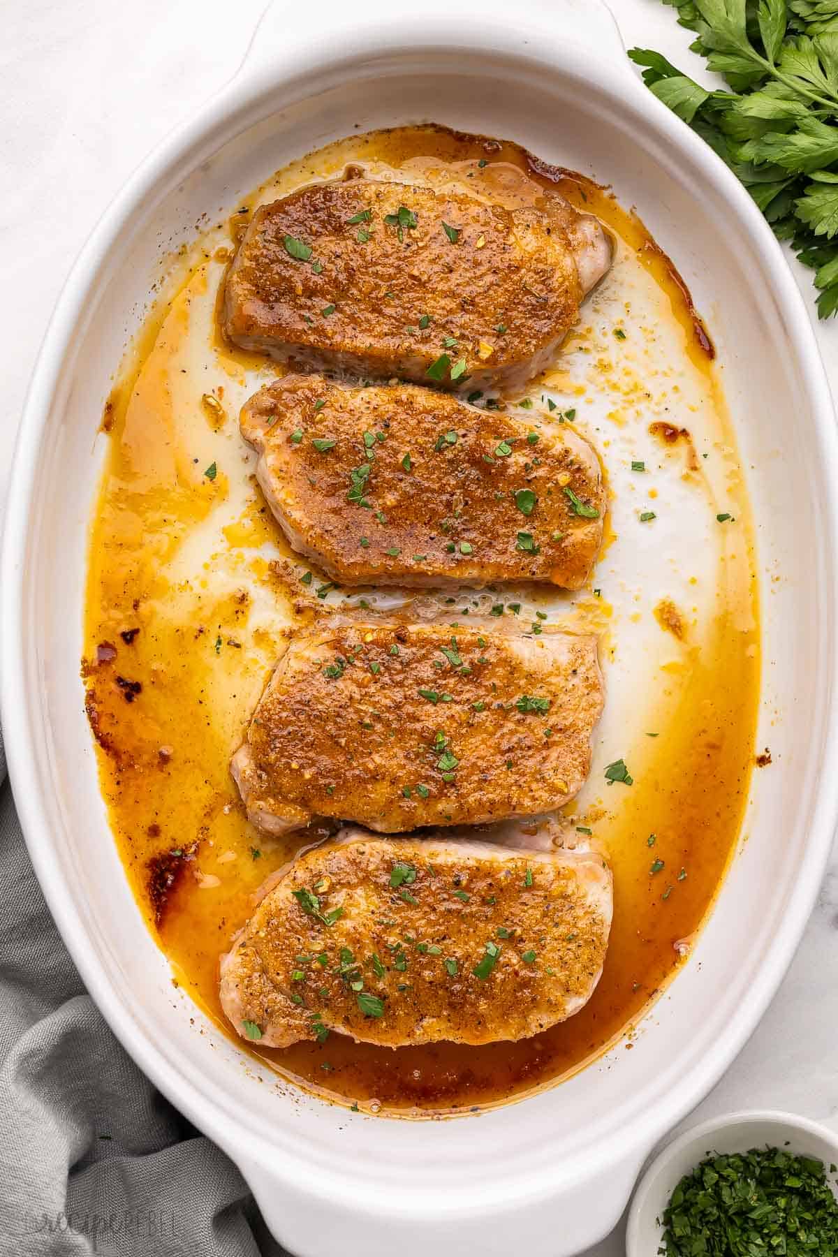 These Baked Pork Chops come out tender and juicy every time with a simple homemade spice rub. Made with boneless pork chops, they’re quick, easy, and ready in 20 minutes! #recipe #dinner | pork chops recipes | pork recipes | easy dinner ideas | dinner recipes four baked pork chops in white pan.