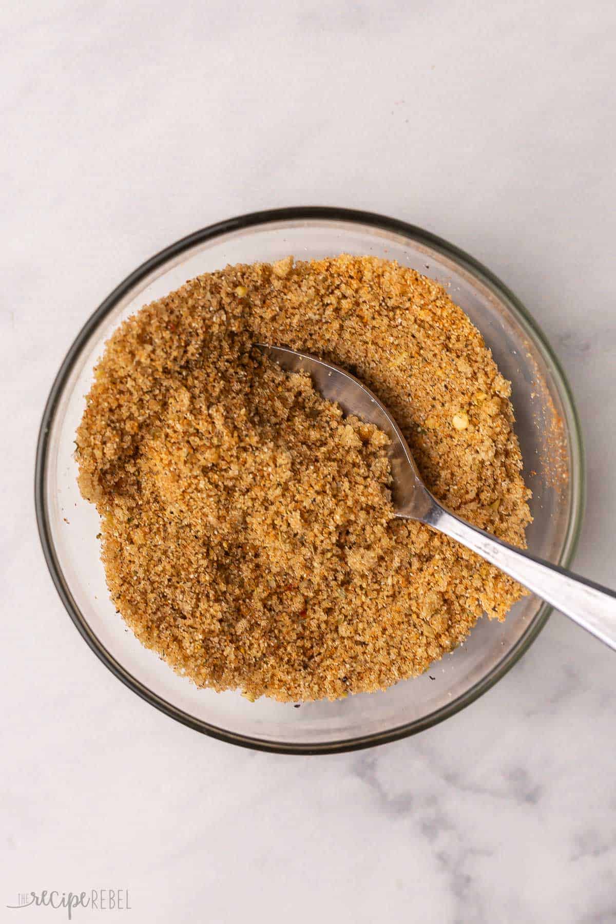 mixed rub ingredients in glass mixing bowl with spoon.