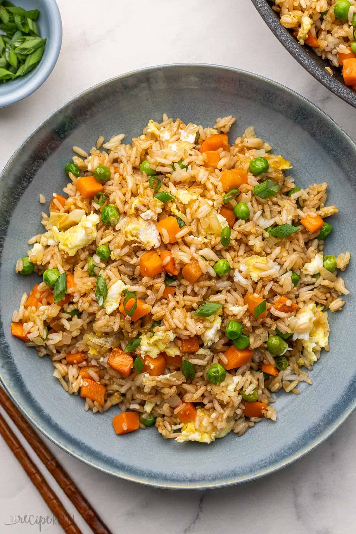 a blue plate filled with fried rice and chopsticks beside.