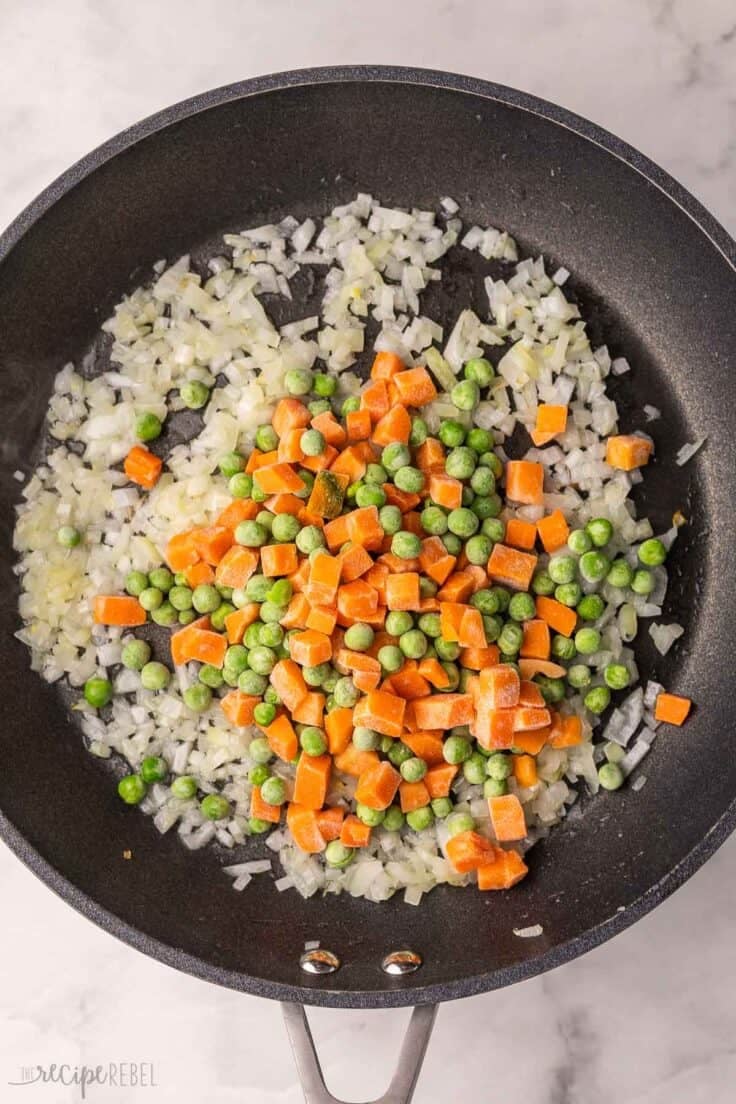 vegetables added to other ingredients in black pan.