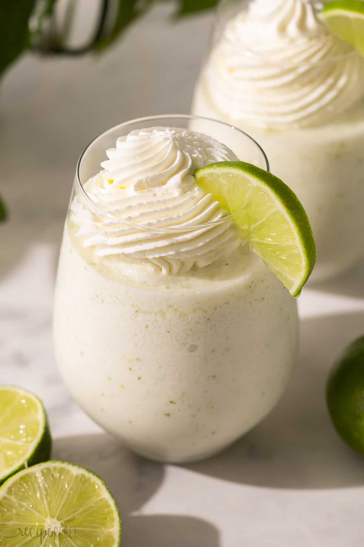 a glass of frozen limeade with a slice of lime on the side.