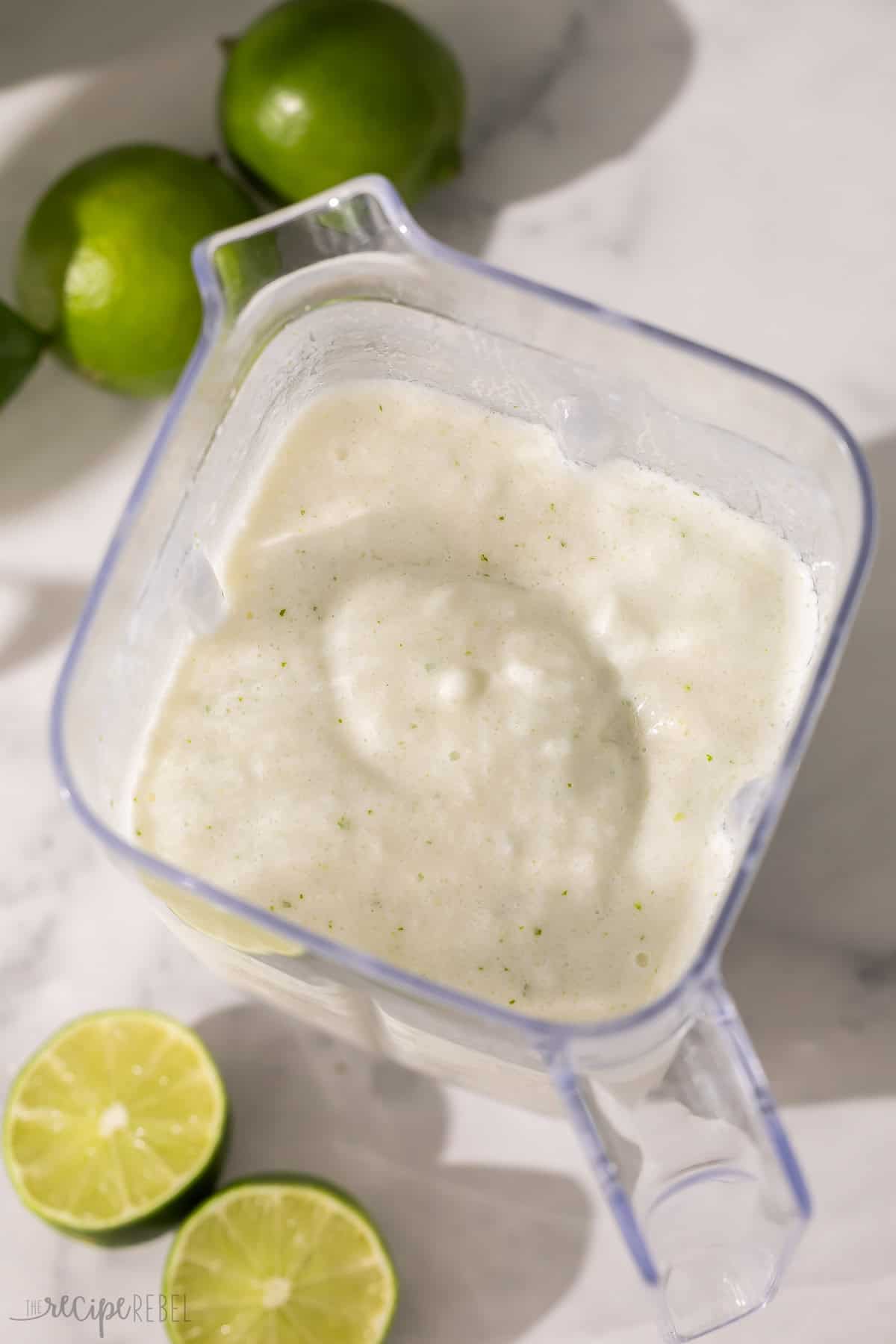 limes beside a blender filled with frozen limeade.