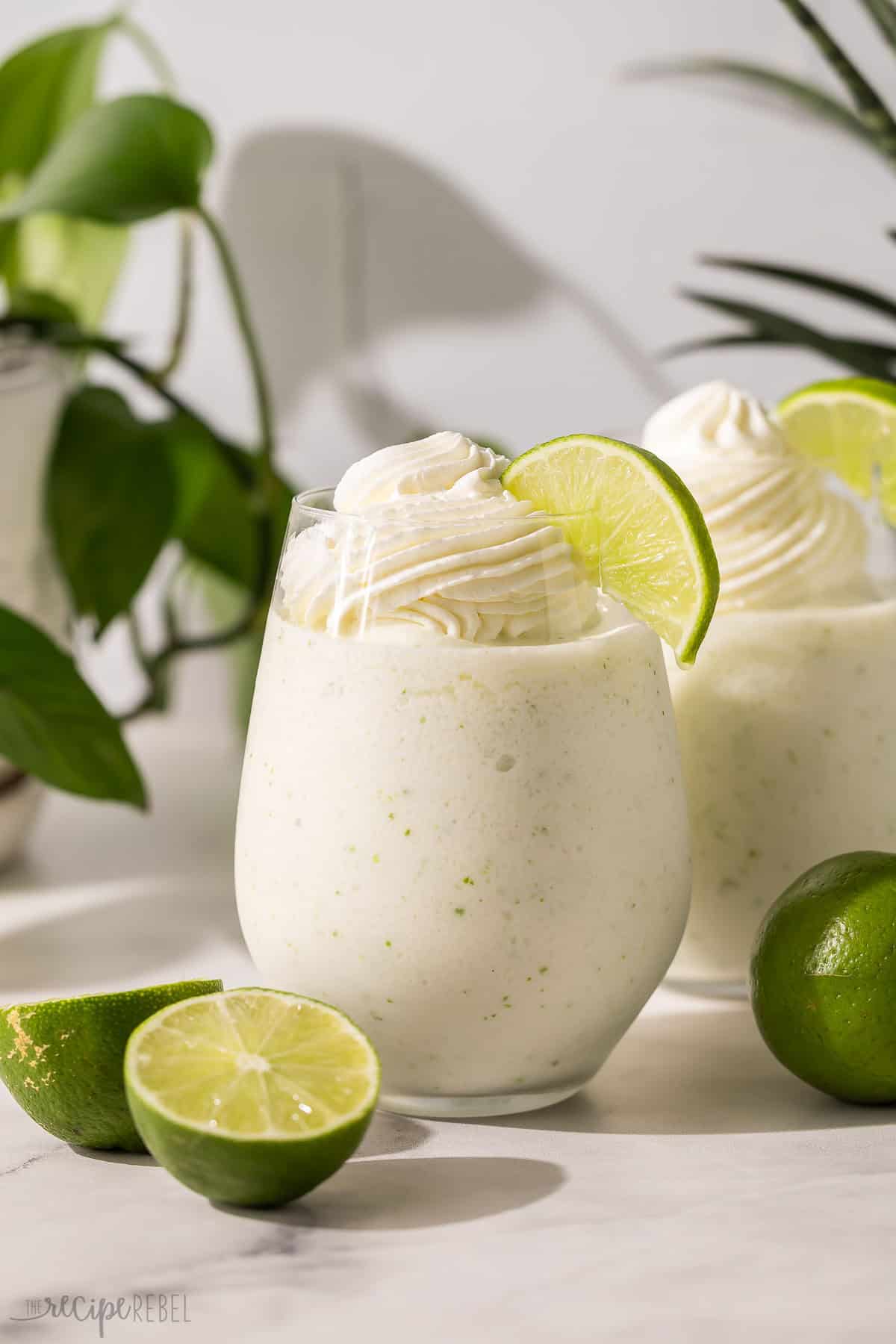 a glass of frozen limeade with sliced limes beside.