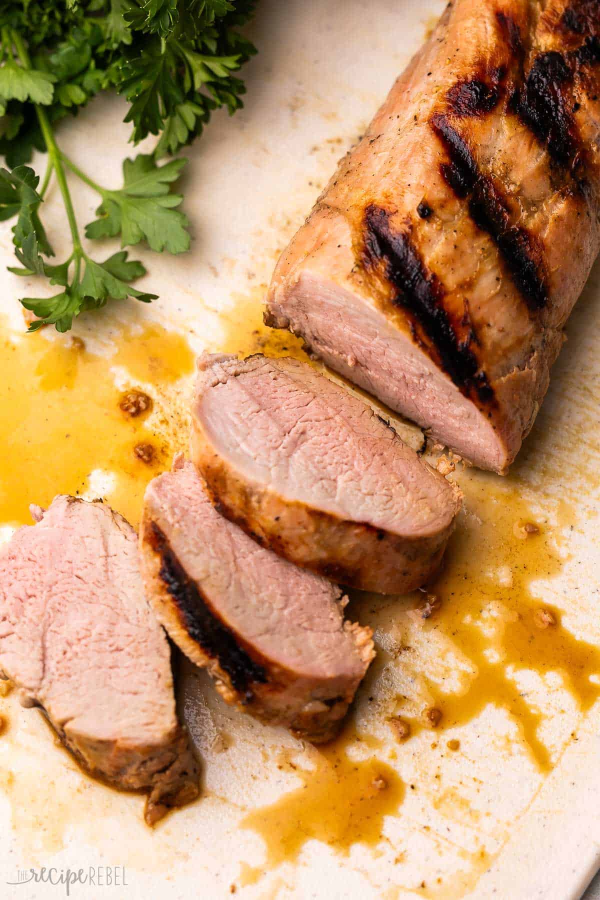 This Grilled Pork Tenderloin has a flavorful marinade and cooks on the grill for a fool-proof main course perfect for summer grilling season! Ready in 30 minutes. Oven and slow cooker options available. #pork #recipe #dinner | grilling recipes | grilling marinades | pork marinade | marinade recipes | how to cook pork tenderloin | summer dinner grilled pork tenderloin on a cutting board.