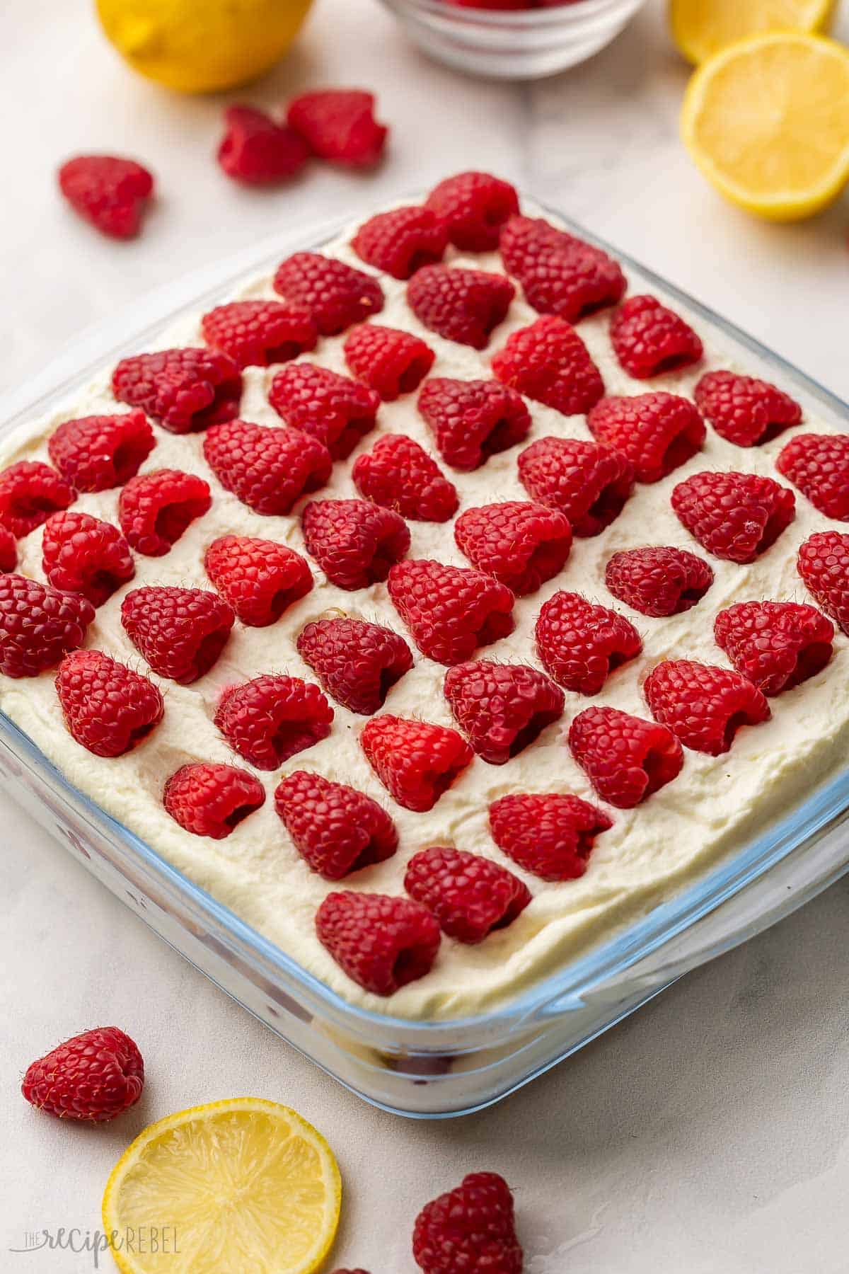 icebox cake with raspberries and lemons around it.