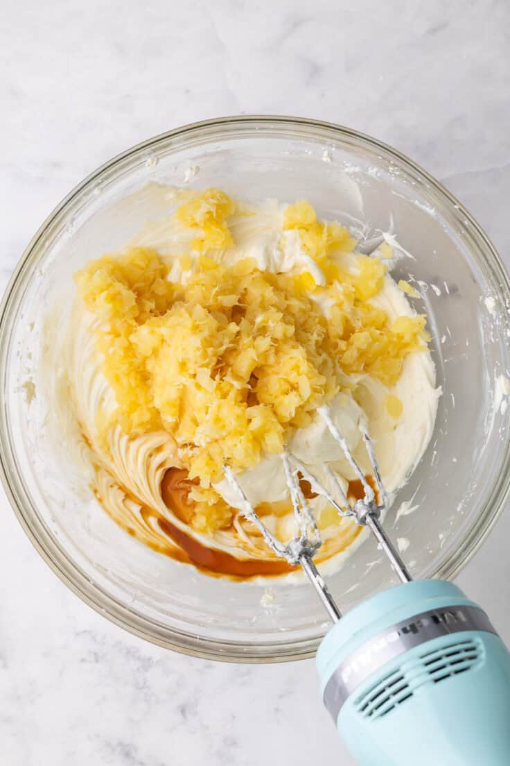 pineapple added to bowl of other ingredients with mixer beside.