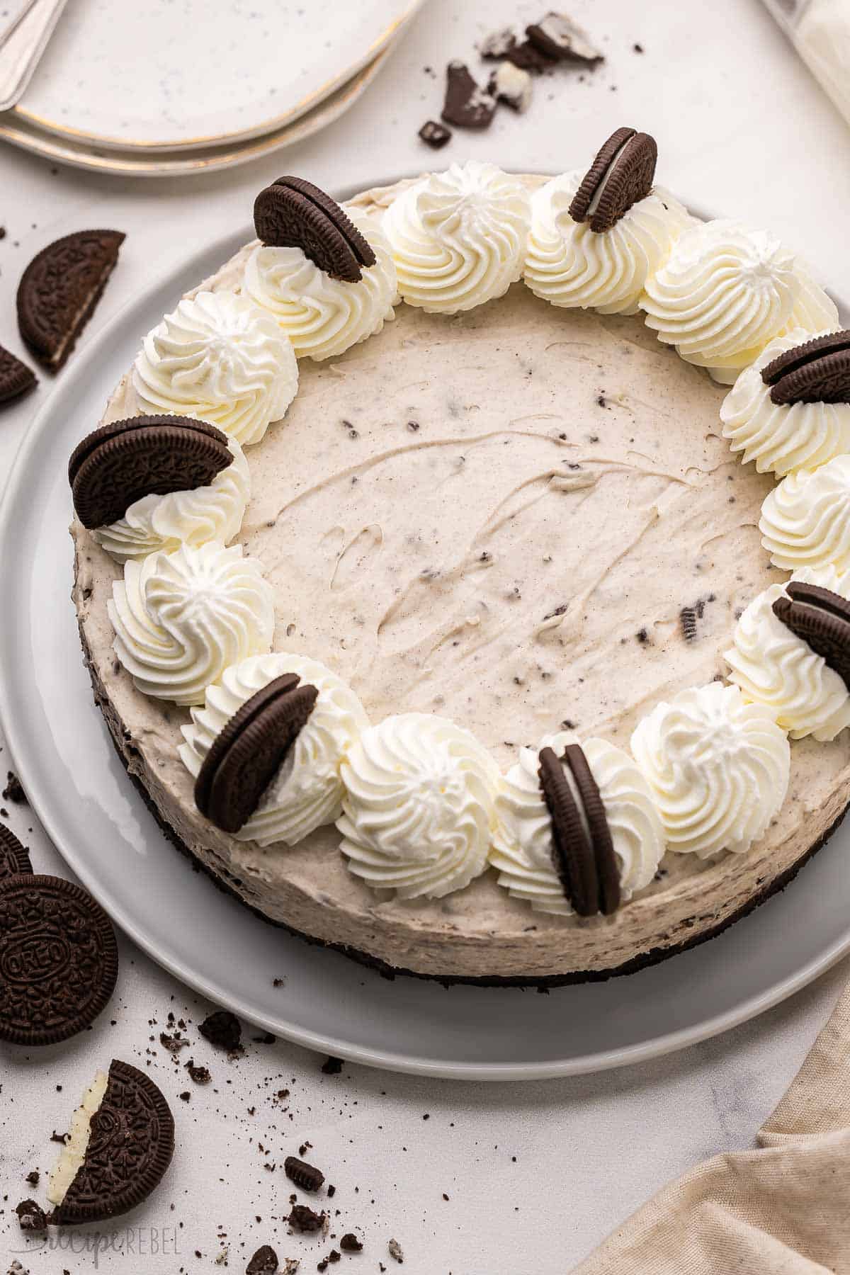 no bake oreo cheesecake on a white plate with oreos scattered beside.